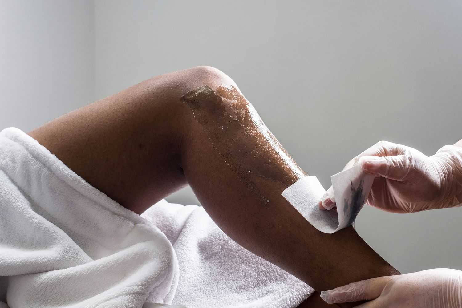 A person receiving a leg waxing treatment in a spa setting.
