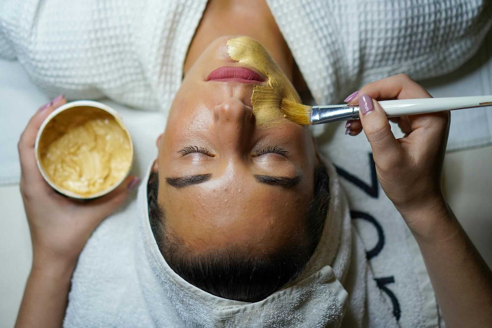 Facial treatment with a gold mask applied by a beautician at a spa.