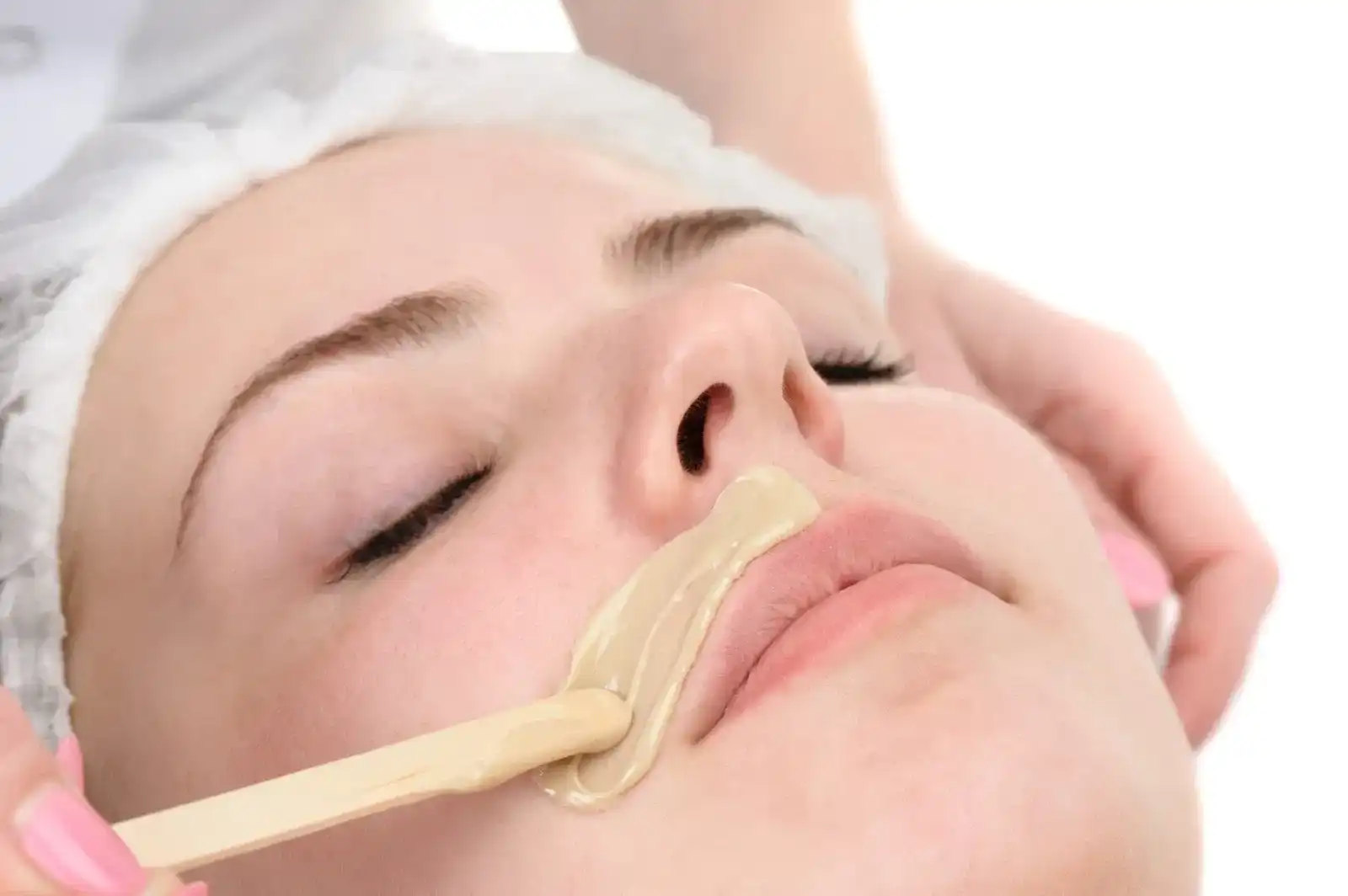 Facial waxing treatment applied to a woman's upper lip.