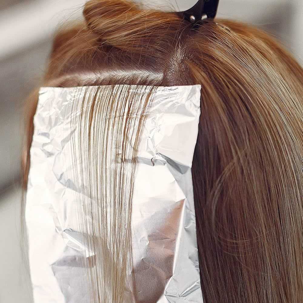 Hair highlighting process with foil in a salon setting.